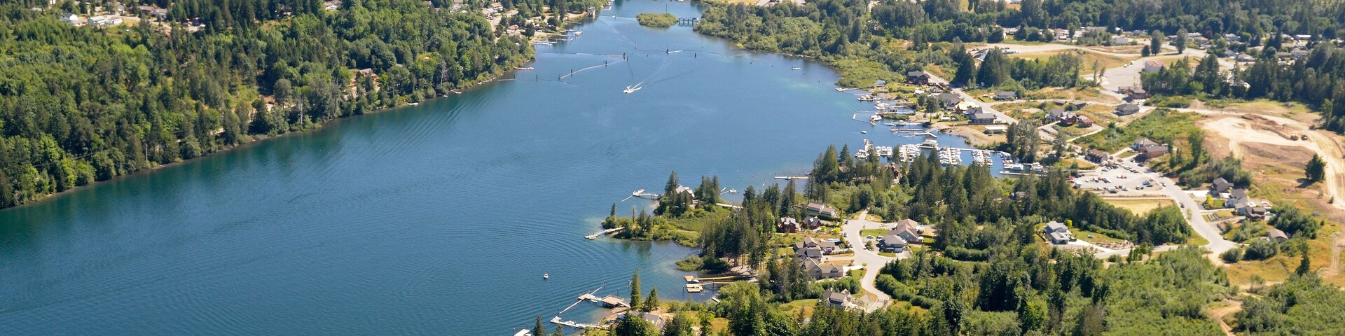 A lake surrounded by dense forests and a small town with visible buildings and docks.