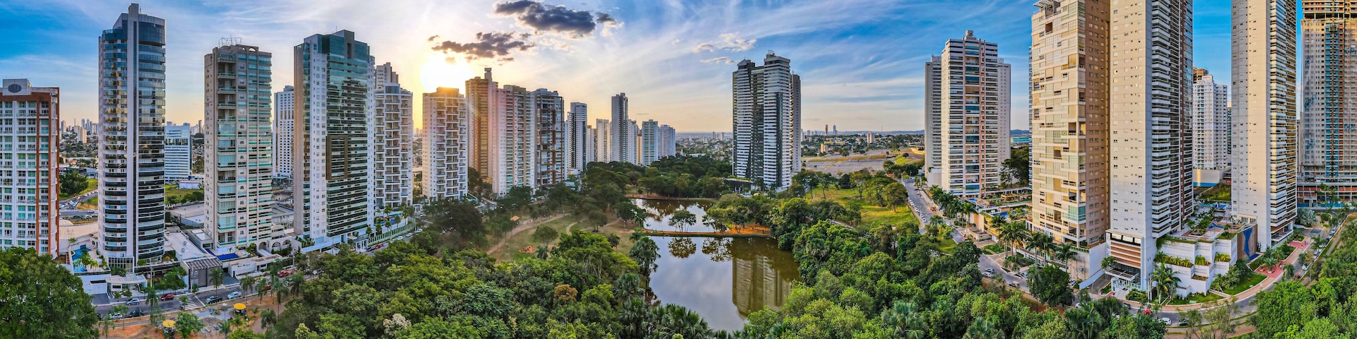 A cityscape with high-rise buildings, a lake, and lush greenery.