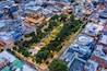 An aerial view of a cityscape with modern buildings, a park, and a circular structure.
