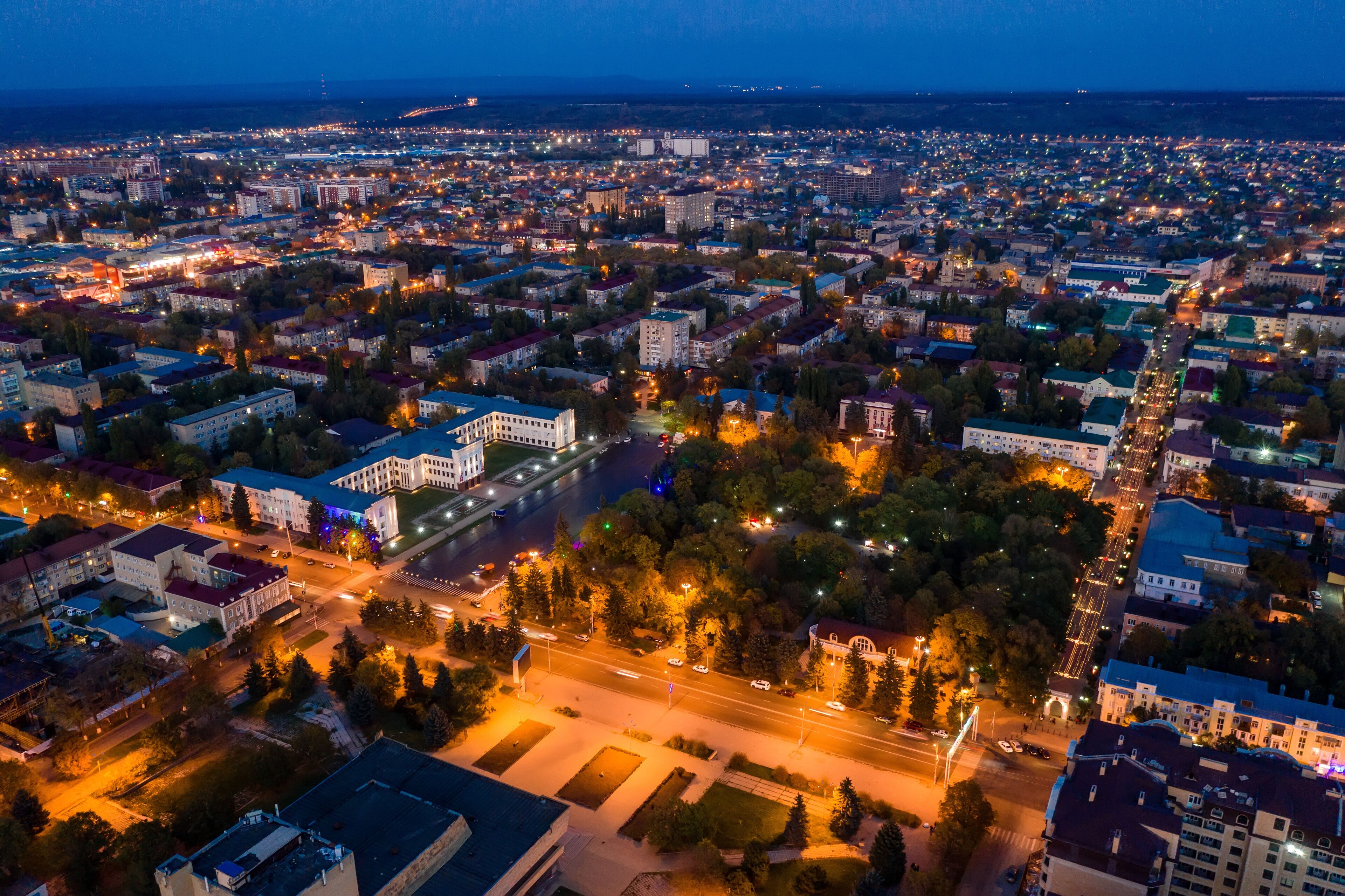 An aerial view of a city at dusk with illuminated streets and buildings.