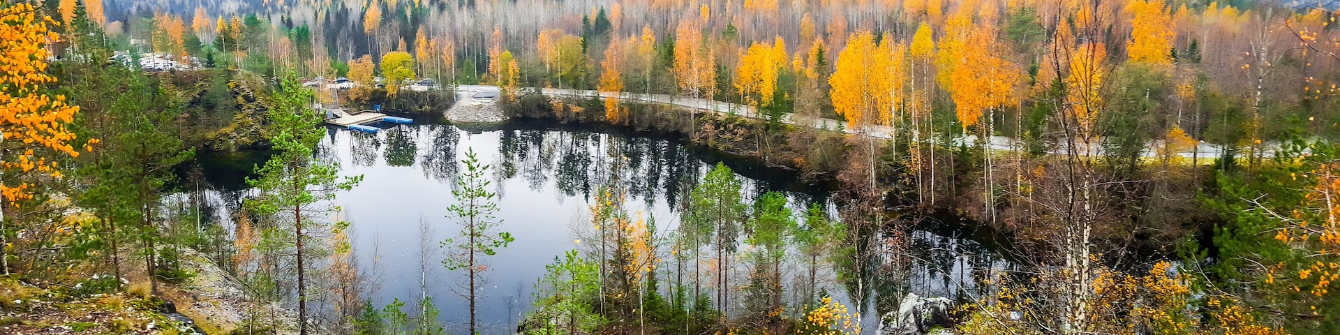 A lake surrounded by autumn-colored trees and a bridge.