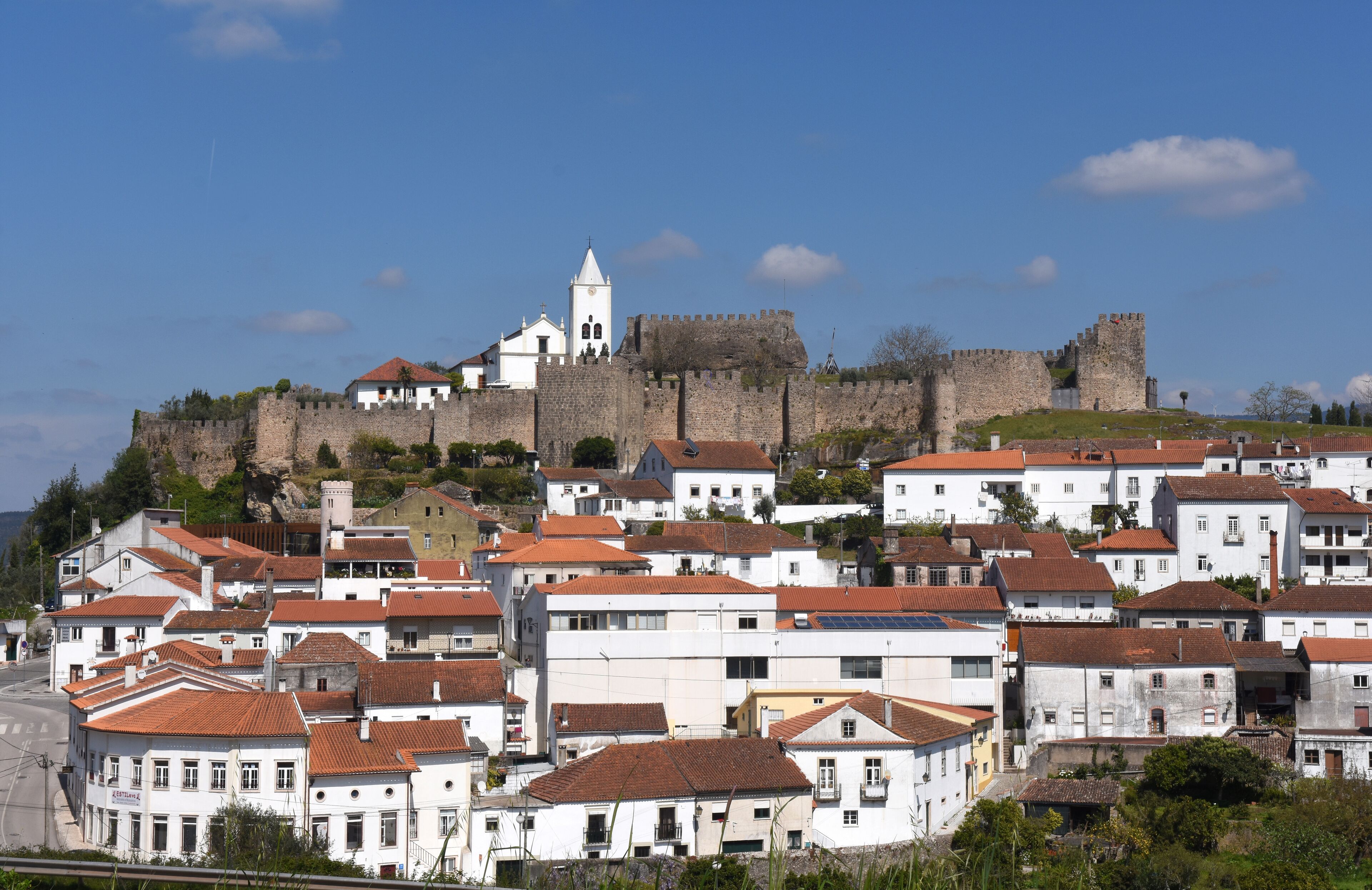 A historic town with white buildings and a large castle on a hill.