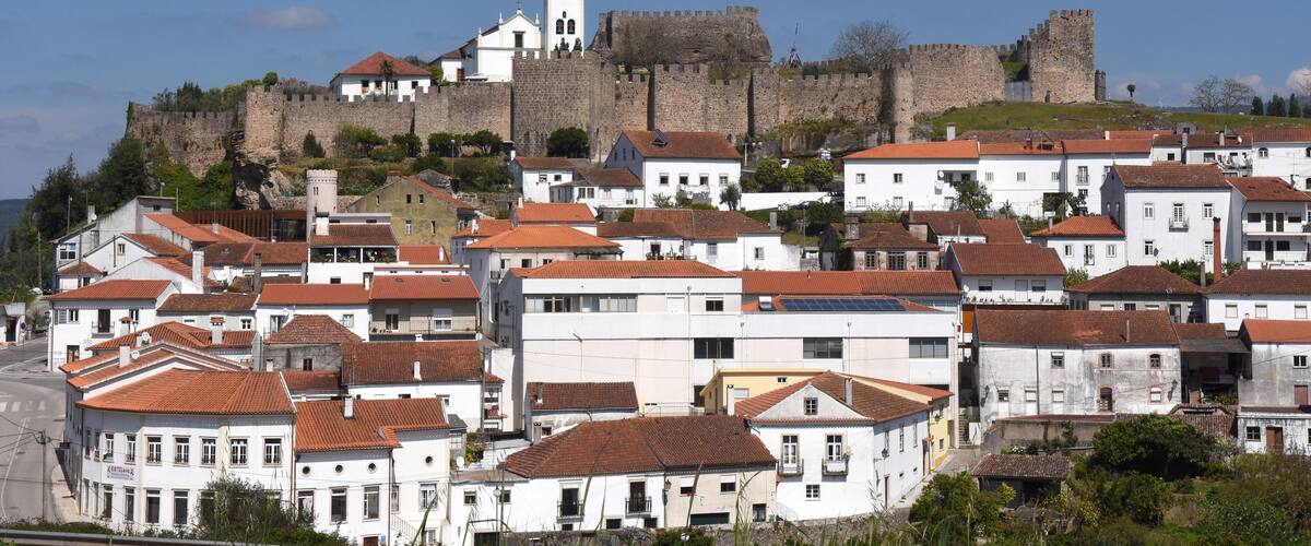 A historic town with white buildings and a large castle on a hill.