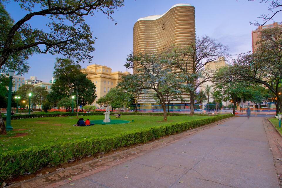 A park with a curved building, trees, and a paved walkway.
