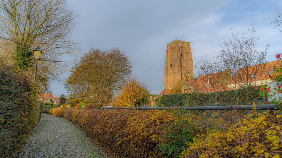 A cobblestone path, a brick church, and autumn foliage.