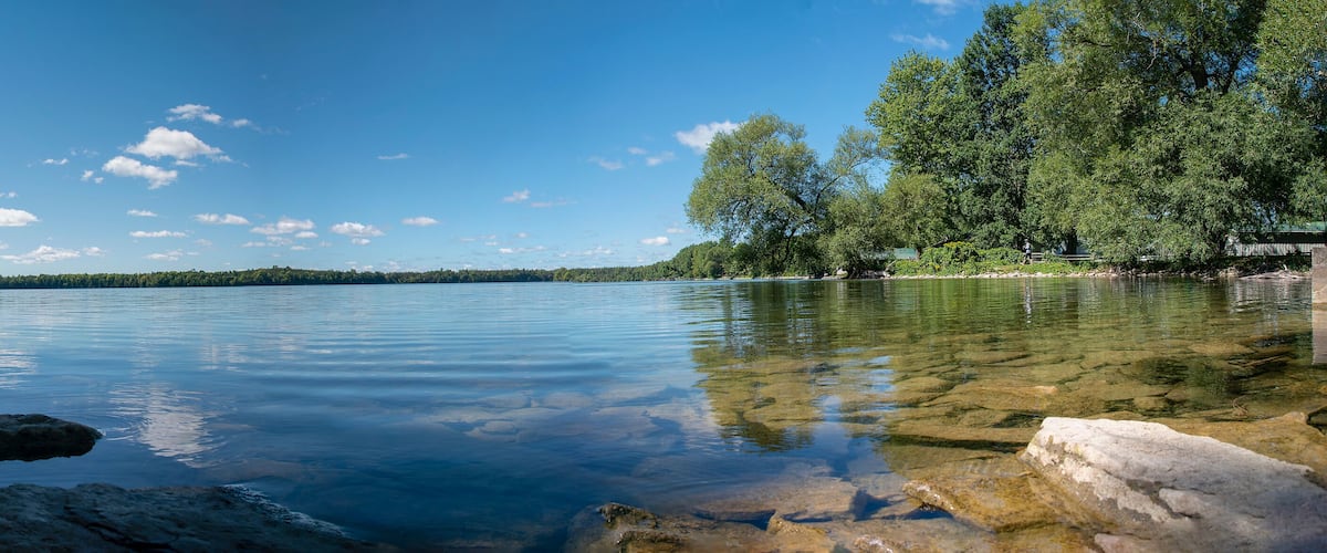 A calm lake surrounded by rocks and trees under a clear sky.