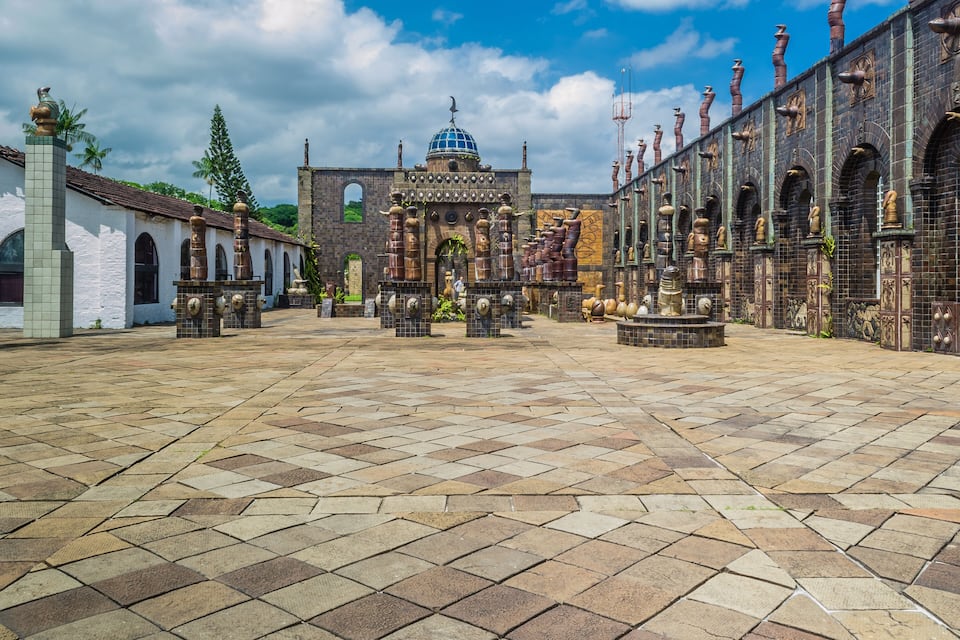 Pátio com uma cúpula central, soalho em azulejos e uma série de arcos com estátuas.