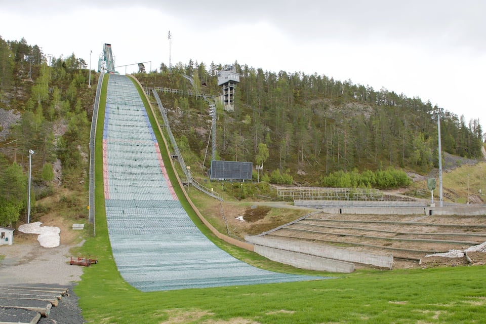 Un trampolín de esquí con una pendiente larga y pronunciada, y una plataforma de observación en la cima.
