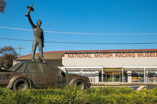 Une statue représentant une personne tenant un mégaphone devant un bâtiment portant l’inscription « Musée national de l’histoire de l’automobile et de la course ».