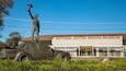 Eine Statue zeigt eine Person, die ein Megaphon vor einem Gebäude hält, das mit "National Motor Racing Museum" beschriftet ist.