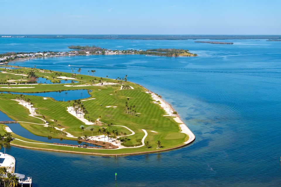 A golf course surrounded by water and palm trees.