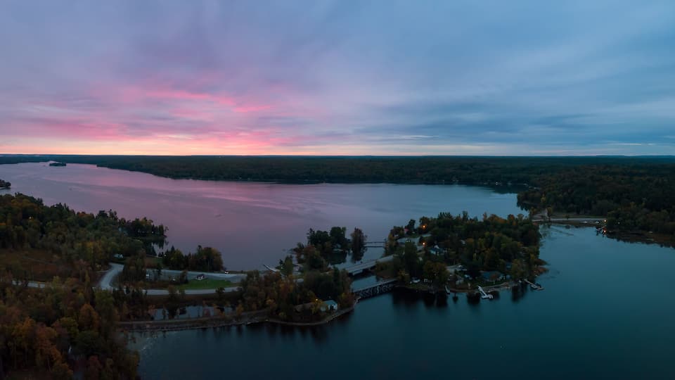 A lake surrounded by forested hills during twilight.