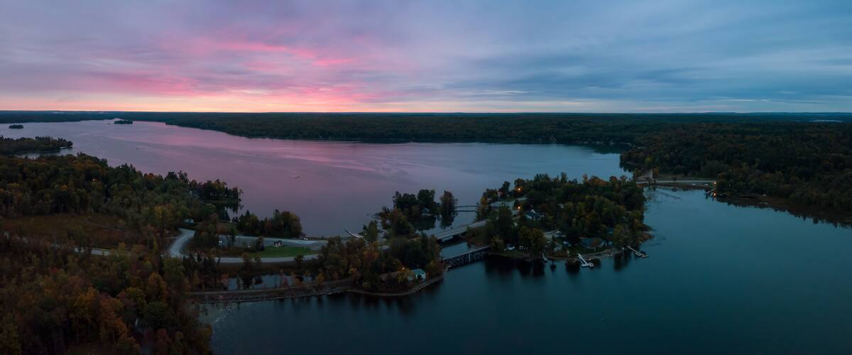 A lake surrounded by forested hills during twilight.