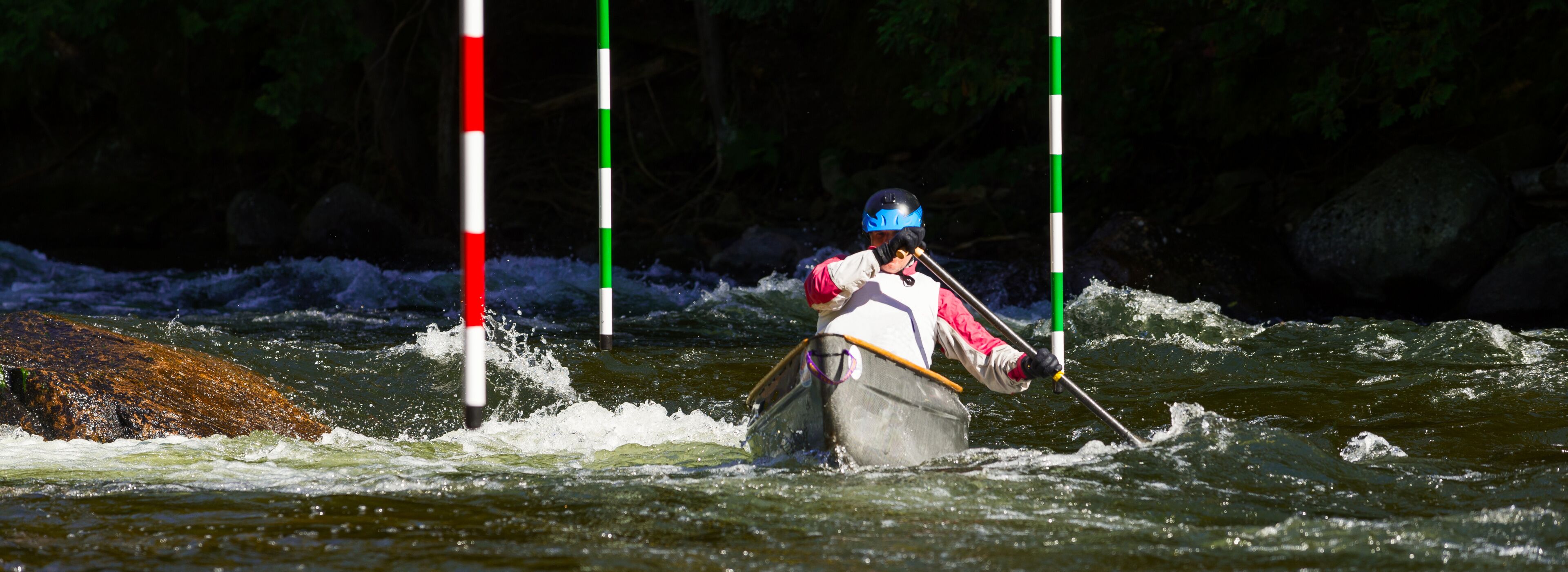 Unidentified paddler steering his canoe through the slalom gates and rapids on Gull River in Minden