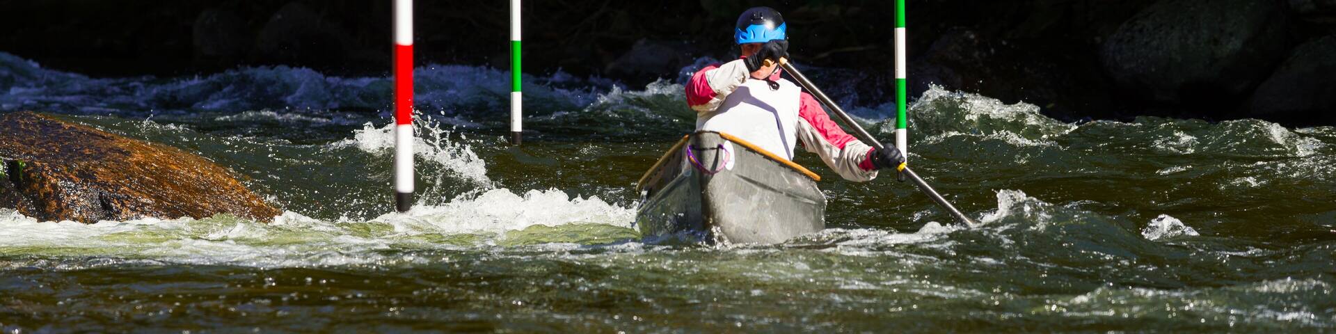Unidentified paddler steering his canoe through the slalom gates and rapids on Gull River in Minden