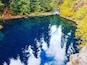 Un lago azul y transparente rodeado de un bosque verde exuberante y terreno rocoso.