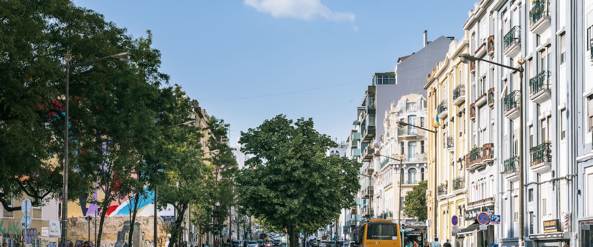 A city street with a green bike lane, parked cars, and a yellow bus.