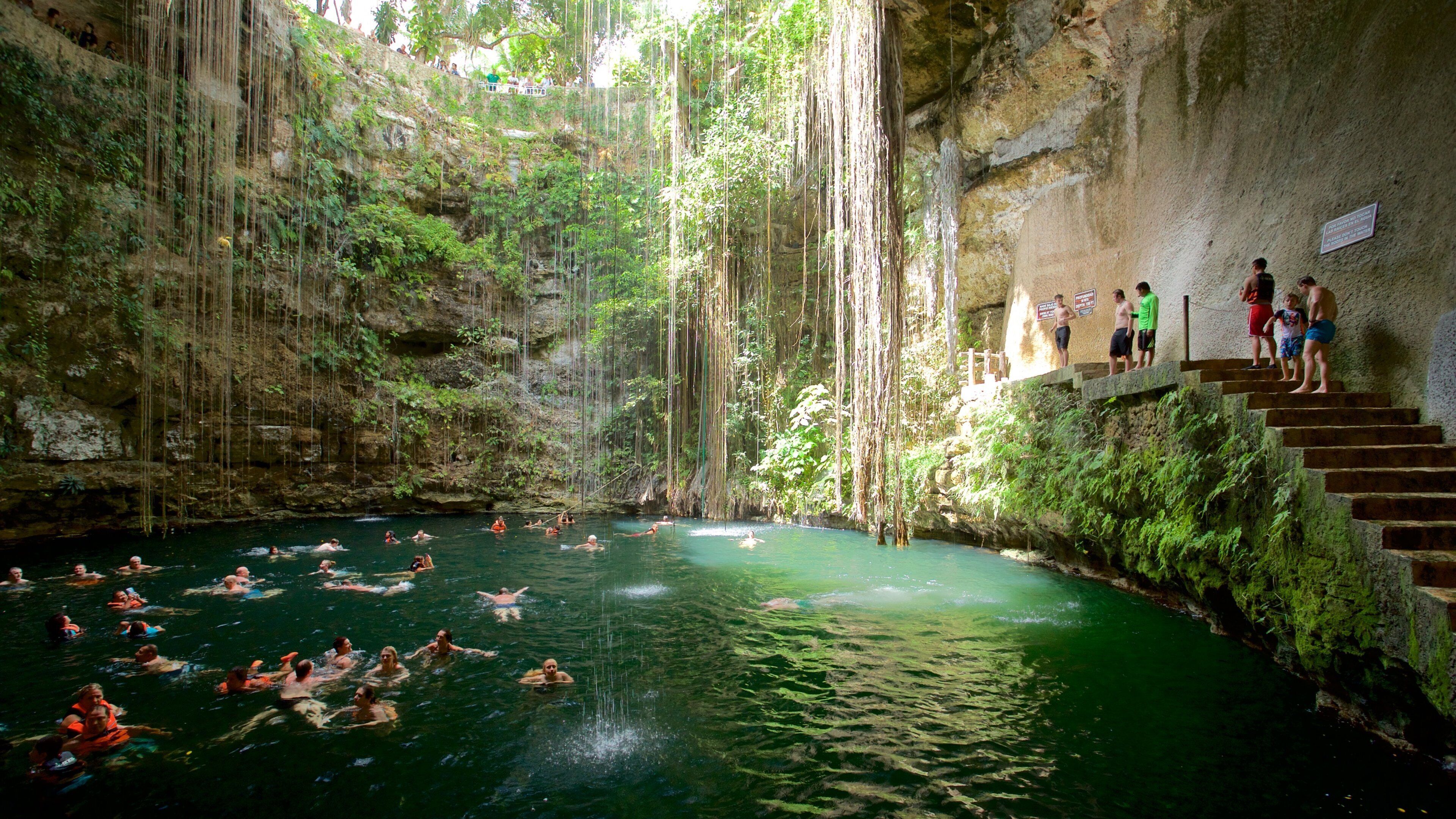 Cenote Ik kil showing a lake or waterhole and swimming as well as a small group of people