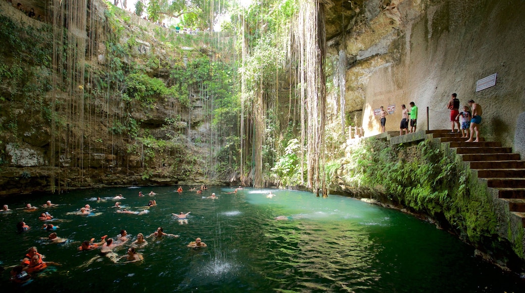 Cenote Ik kil showing a lake or waterhole and swimming as well as a small group of people
