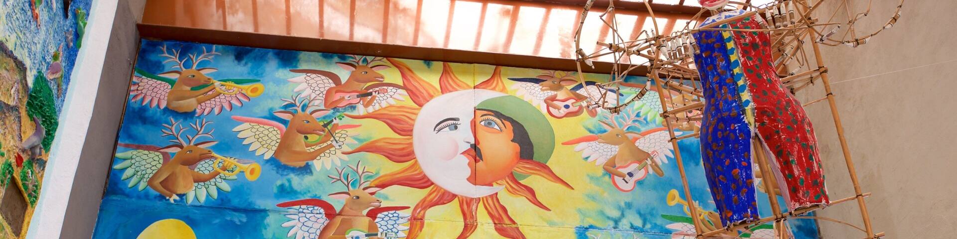 Un mural vibrante con un sol central, rodeado de diversas figuras y animales.