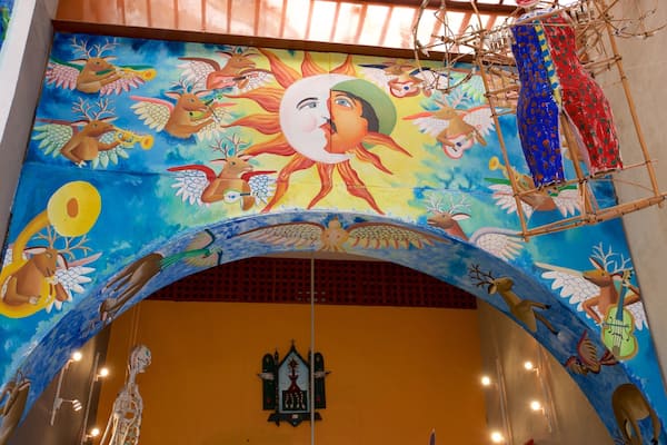Une fresque colorée, dont le motif central est un soleil, entouré de différents animaux et personnages.