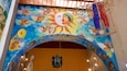 A vibrant mural with a central sun, surrounded by various animals and figures.
