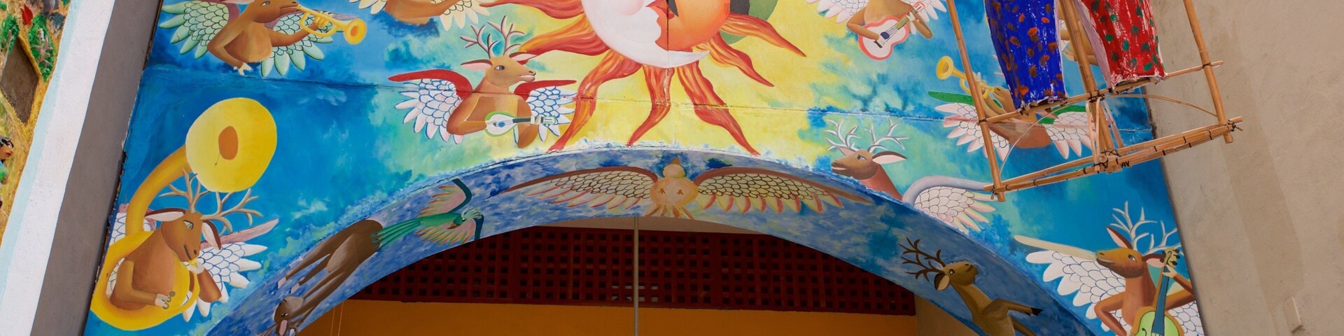 Um mural vibrante com um sol central, rodeado por diversos animais e figuras.