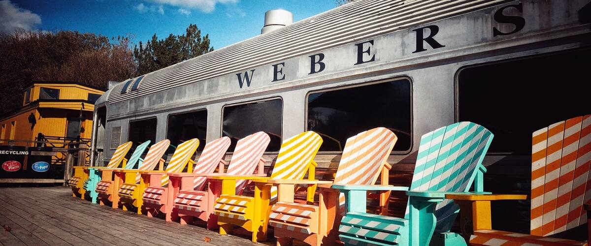 A train with colorful Adirondack chairs lined up in front.
