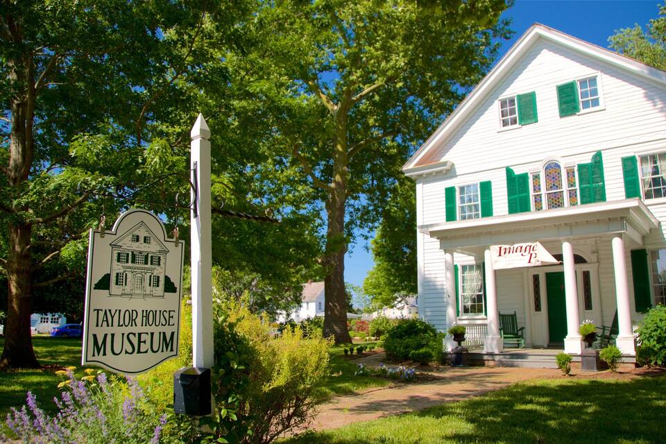 A white house with green shutters and a sign for Taylor House Museum.