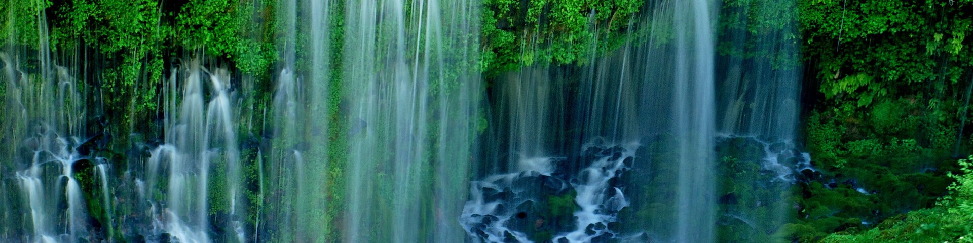 Water leaking between rock layers to form veil like falls, Burney Falls, California