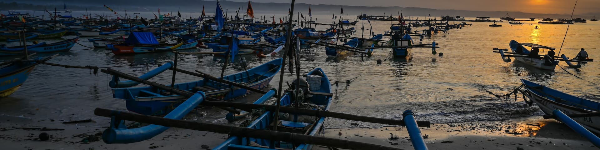 Sunrise on Indonesian Pangandaran beach with white sand and fishing boats