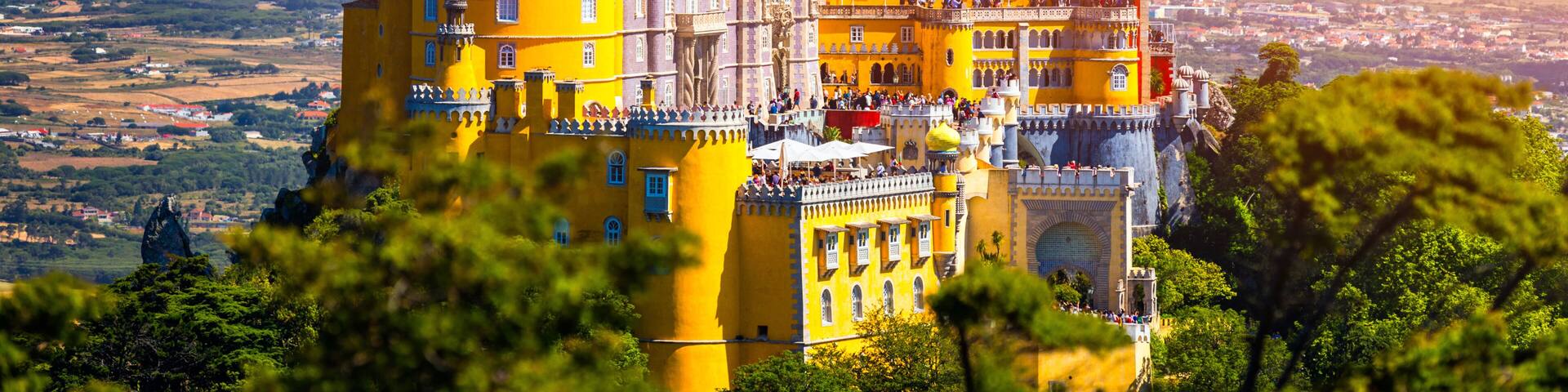 Famous historic Pena palace part of cultural site of Sintra against sunset sky in Portugal. Panoramic View Of Pena Palace, Sintra, Portugal. Pena National Palace at sunset, Sintra, Portugal.