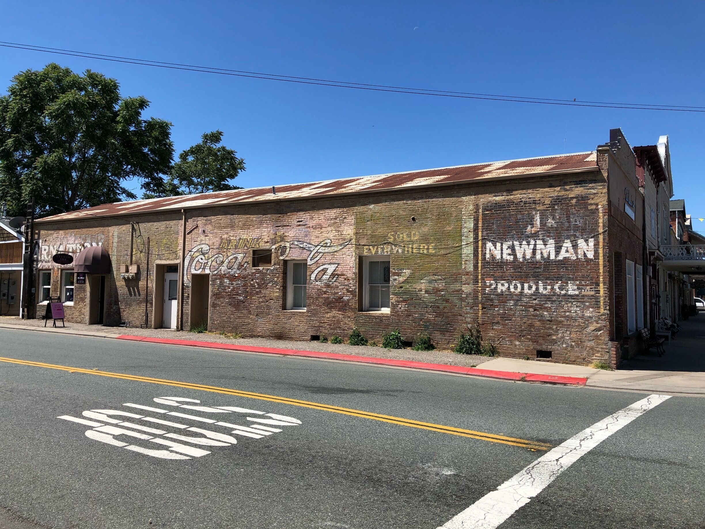 Remnants of what were once billboard ads on the side of what looks like a former food store in Ione California.
