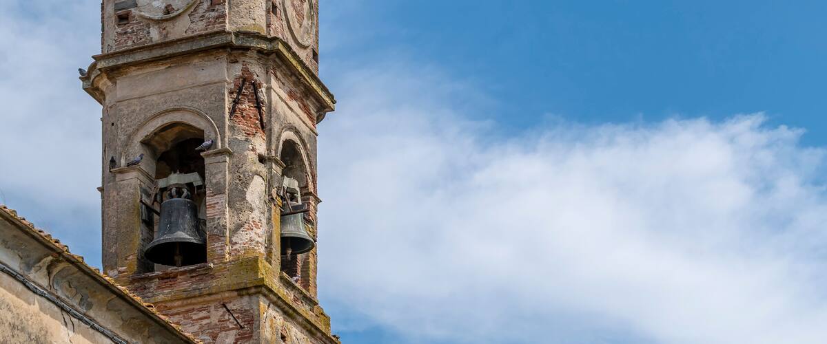 A historic clock tower with visible wear and a clear sky in the background.
