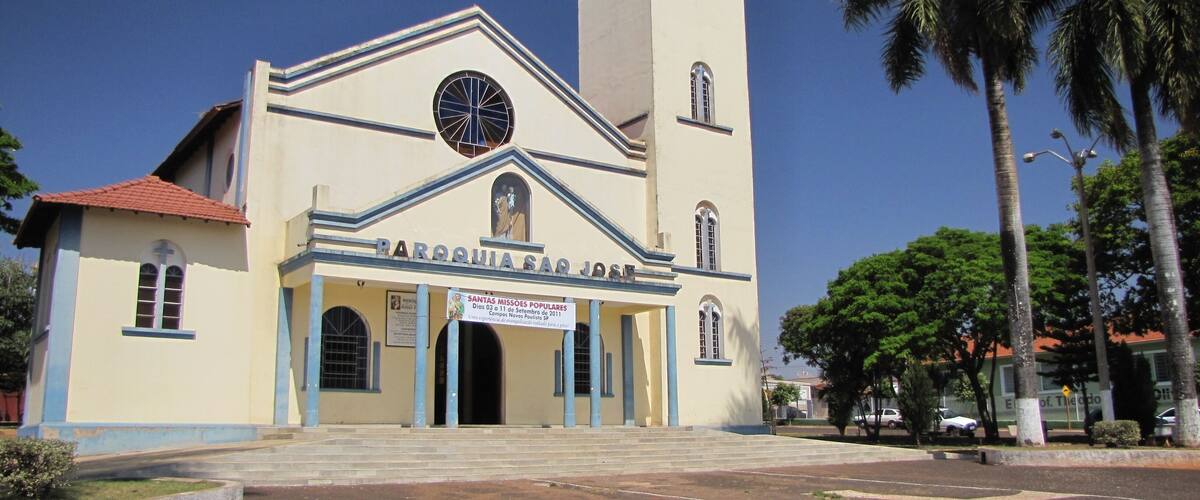 A church with a clock tower and a sign for 'Santas Missoes Populares'.
