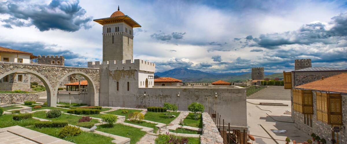 A historic town with stone walls, a central tower, and a well-maintained garden.