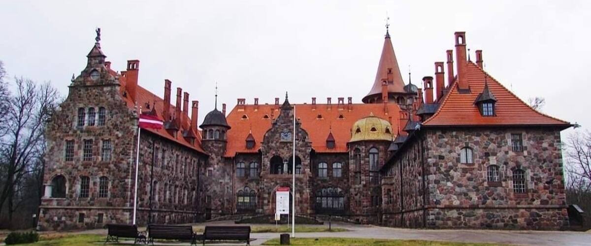 A historic stone building with multiple towers and a red roof.