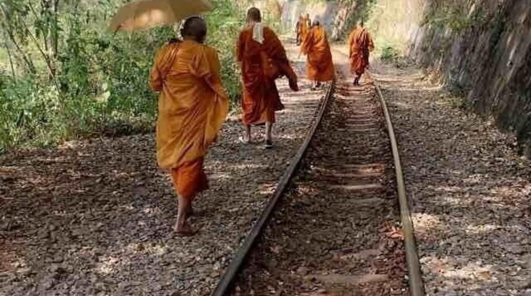 Monks on the tracks of the popular tourist train line going through Kanchanaburi Province, along the Kwai river and on its famous bridge, Western Thailand.