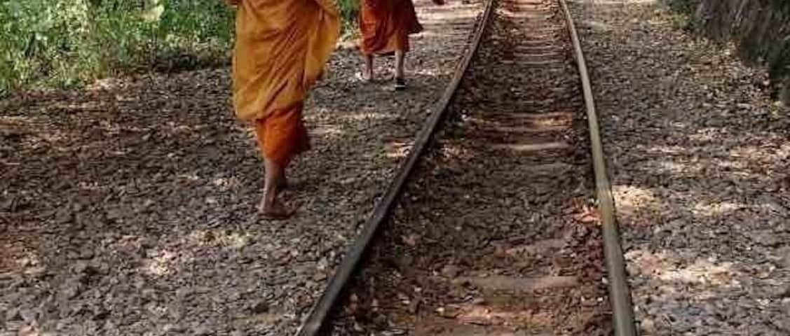 Monks on the tracks of the popular tourist train line going through Kanchanaburi Province, along the Kwai river and on its famous bridge, Western Thailand.