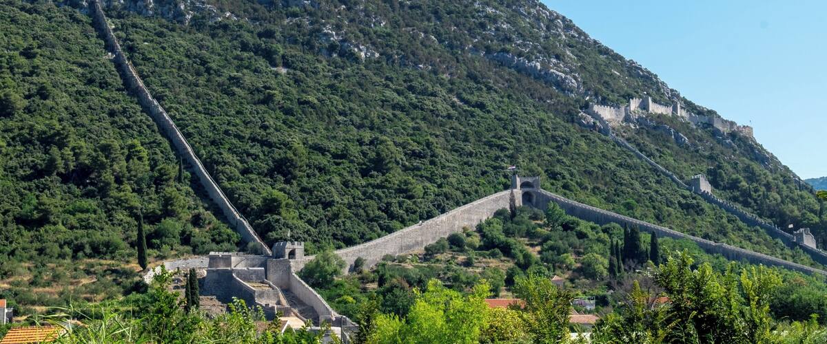 A mountainous landscape with a stone bridge and ancient ruins.