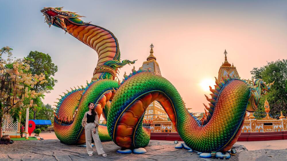 Rainbow carve serpent or colorful Thai Naga and asian woman standing in the sunset at Wat Phra That Nong Bua temple