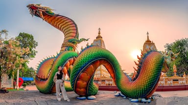 Rainbow carve serpent or colorful Thai Naga and asian woman standing in the sunset at Wat Phra That Nong Bua temple