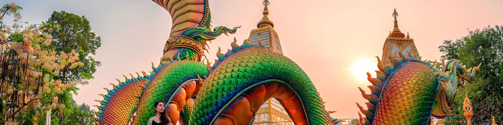 Rainbow carve serpent or colorful Thai Naga and asian woman standing in the sunset at Wat Phra That Nong Bua temple