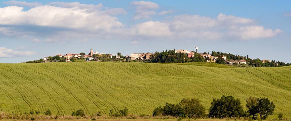 A green hillside with scattered buildings and a tower.