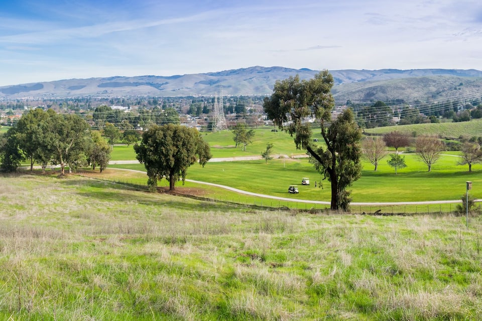 A golf course with a scenic view of rolling hills and distant mountains.