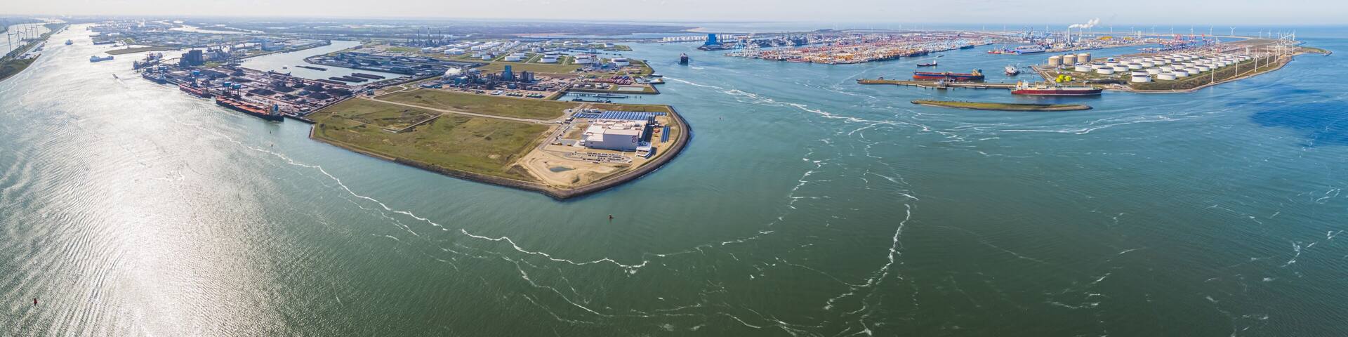 Aerial shot over harbor area, industrial landscape, oil storage containers and tanker ships, blue sky in the background, Maasvlakte, Netherlands. High quality photo