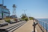 A wooden boardwalk with benches, a lighthouse, and a clear view of the water.