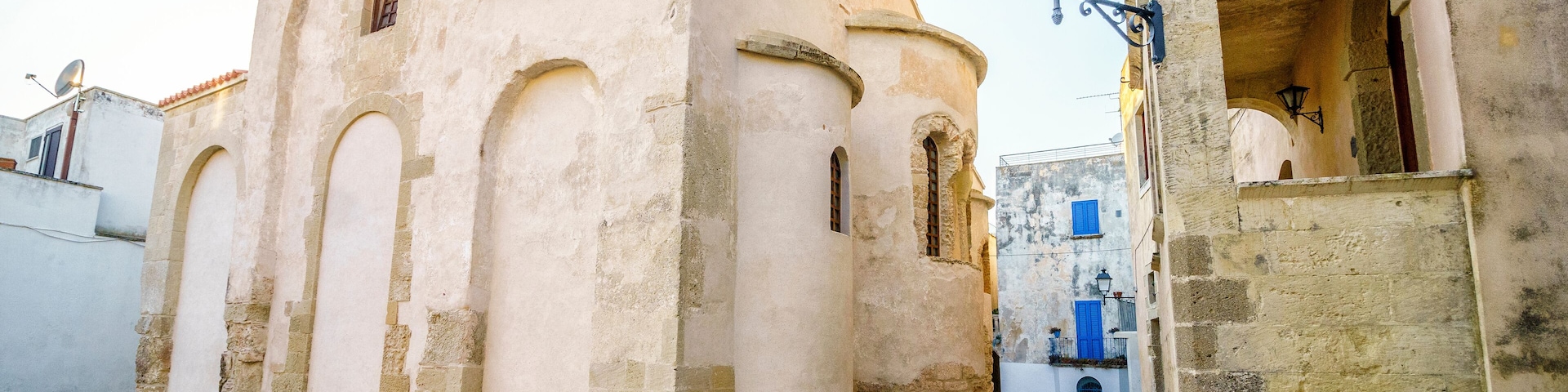 Una calle adoquinada con un edificio histórico que tiene ventanas arqueadas y un tejado de tejas.