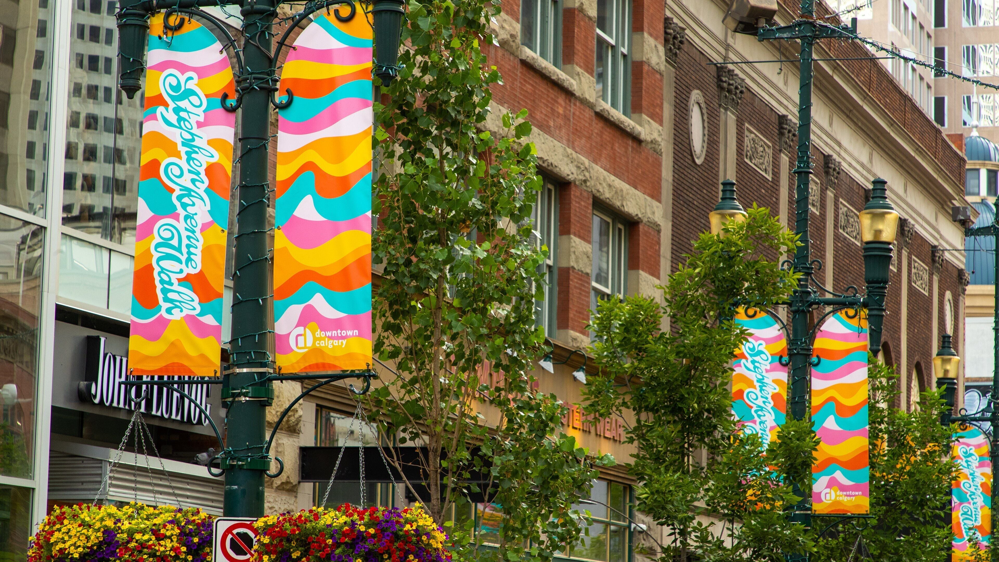 Colorful banners hanging from a street lamp, a flower basket, and a building with a sign that reads "downtown calgary".