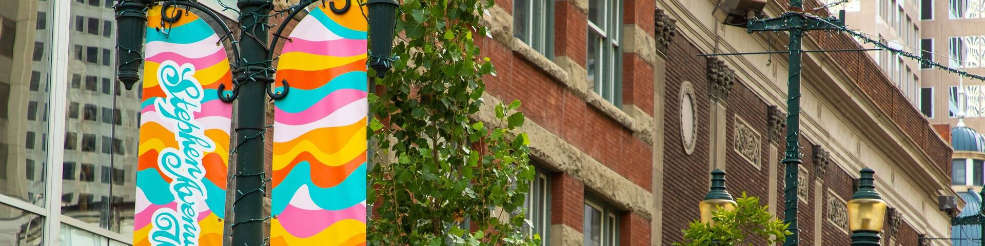 Colorful banners hanging from a street lamp, a flower basket, and a building with a sign that reads "downtown calgary".